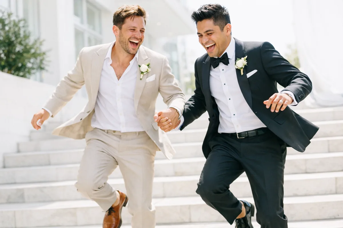 Two grooms running down steps, both laughing