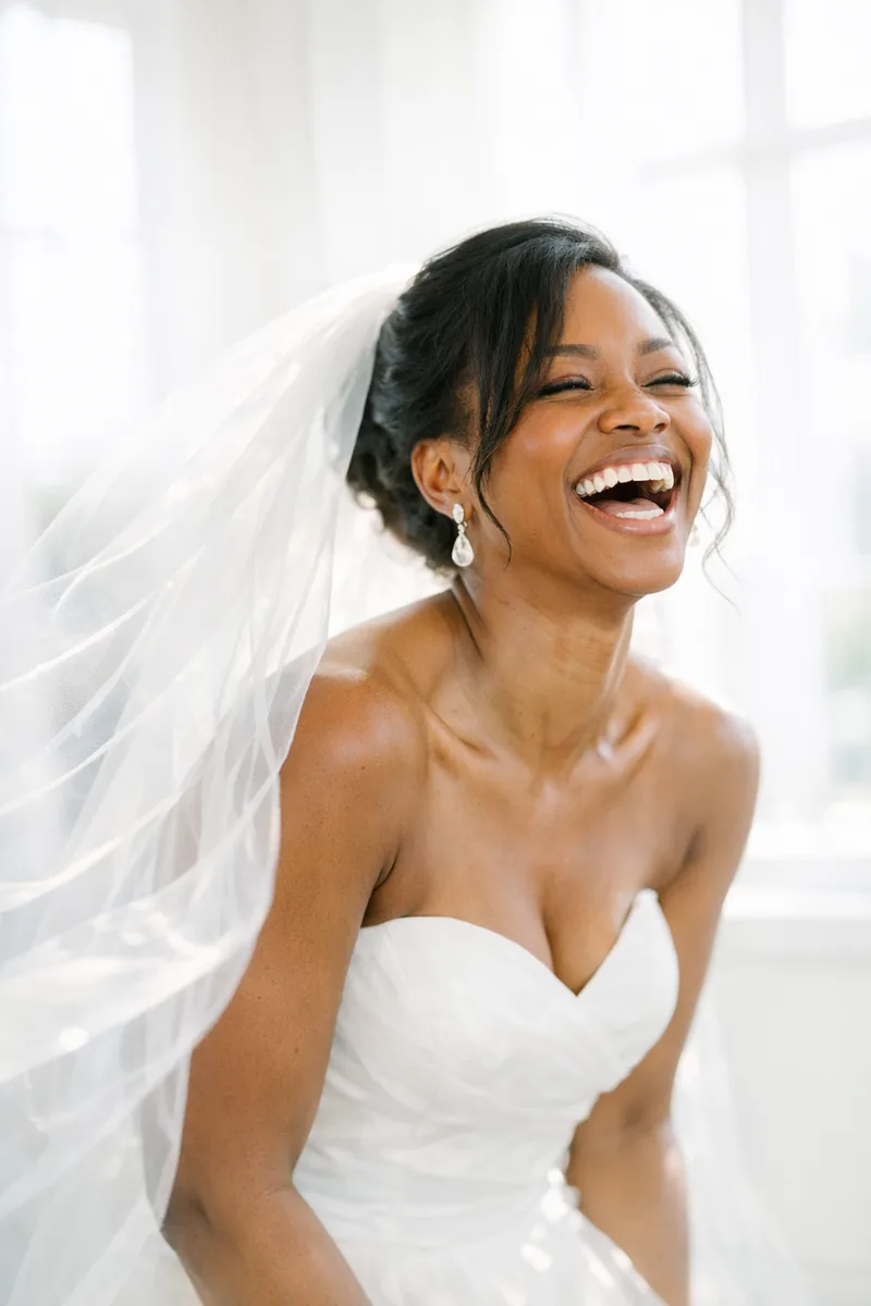 The bride laughing in window light